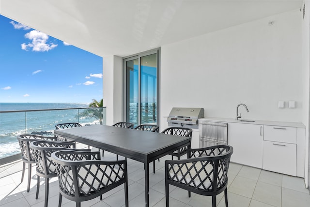 balcony with a water view, sink, and area for grilling