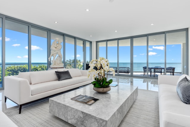 living room with plenty of natural light, a water view, and floor to ceiling windows