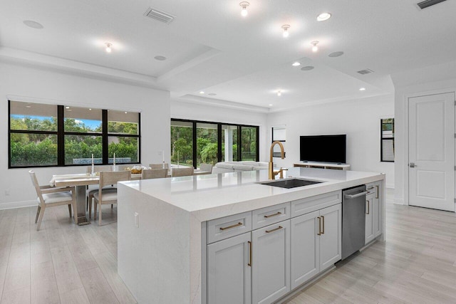 13450 Artisan Cir, Palm Beach Gardens, FL 33418 - kitchen with a sink, stainless steel dishwasher, open floor plan, a tray ceiling, and light wood-style flooring