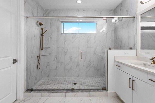 bathroom featuring a shower with shower door and vanity