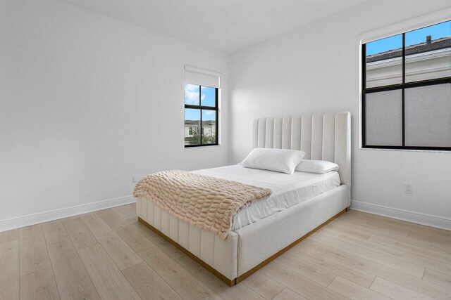 bedroom featuring light wood-type flooring and a nursery area