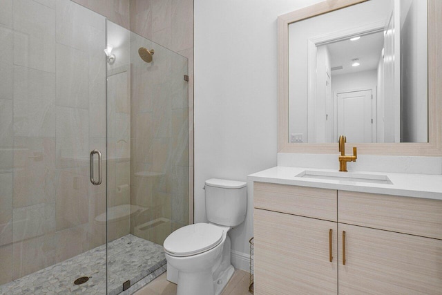 bathroom with a stall shower, vanity, and toilet