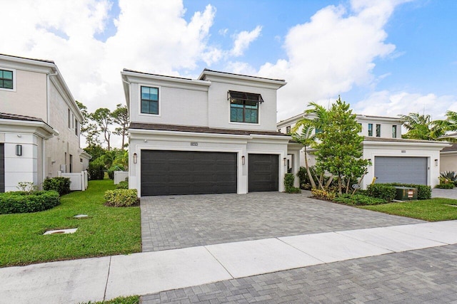 view of front of house with an attached garage, a front yard, decorative driveway, and stucco siding