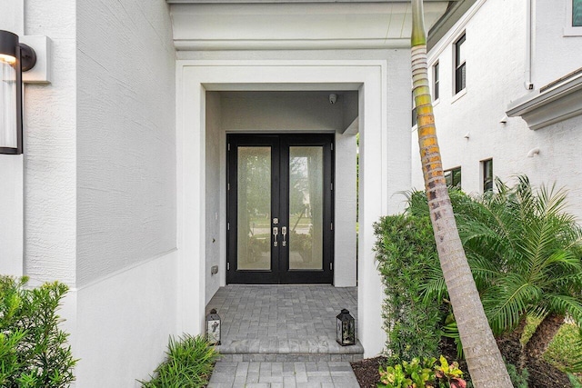 property entrance with stucco siding and french doors