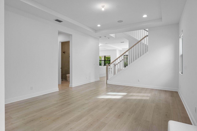 unfurnished living room featuring light wood-type flooring, baseboards, and stairway