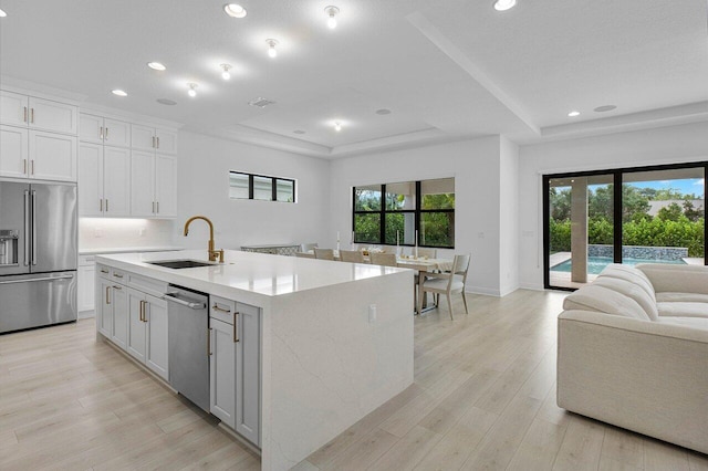 13450 Artisan Cir, Palm Beach Gardens, FL 33418 - kitchen featuring appliances with stainless steel finishes, a sink, a tray ceiling, recessed lighting, and a kitchen island with sink