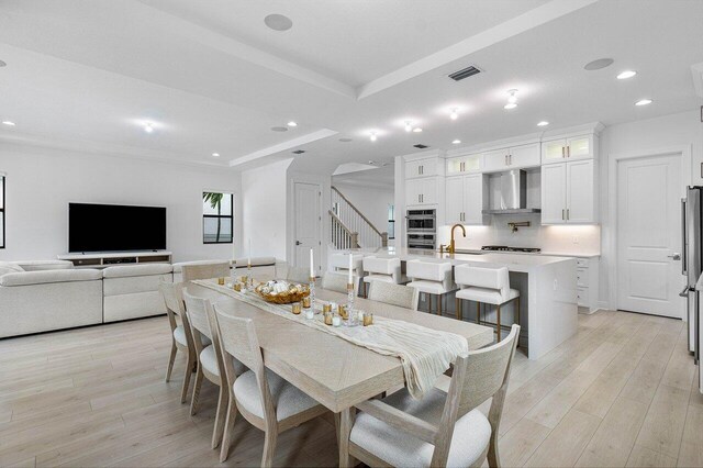 kitchen with light hardwood / wood-style floors, stainless steel appliances, a center island with sink, white cabinets, and sink