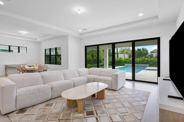 living room with a tray ceiling, light wood-style flooring, and recessed lighting