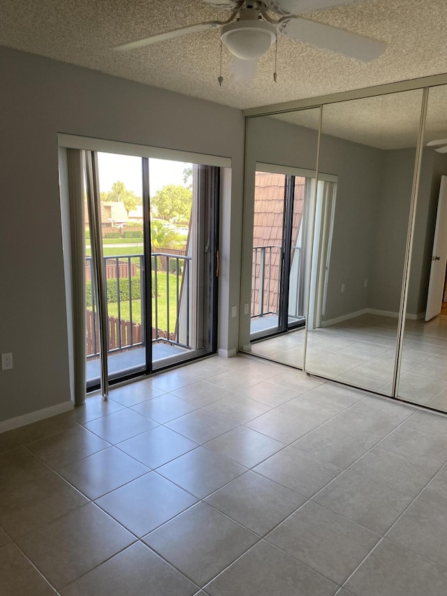 empty room with a textured ceiling, ceiling fan, and light tile patterned flooring