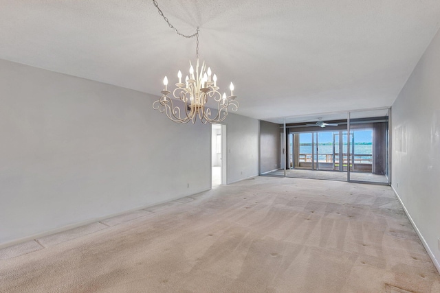 carpeted spare room featuring a chandelier and a textured ceiling