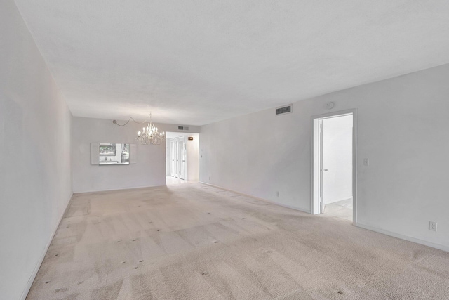 carpeted empty room with a chandelier