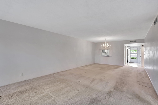 carpeted empty room featuring a notable chandelier