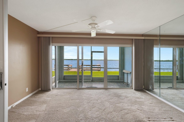 carpeted empty room featuring a water view and ceiling fan