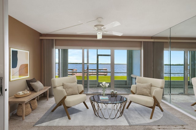 carpeted living room with a water view and ceiling fan