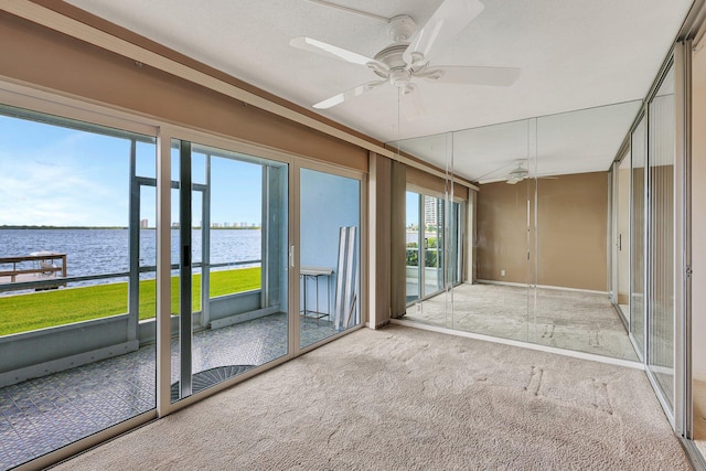 unfurnished sunroom with a water view and ceiling fan