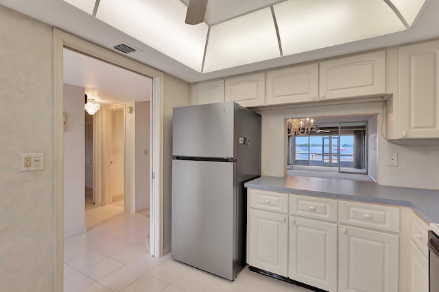 kitchen featuring white cabinetry, a chandelier, stainless steel refrigerator, and light tile patterned floors