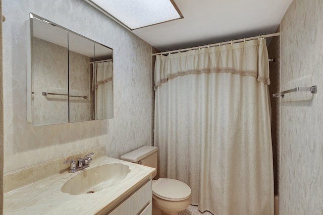 bathroom with toilet, vanity, a skylight, and a shower with curtain