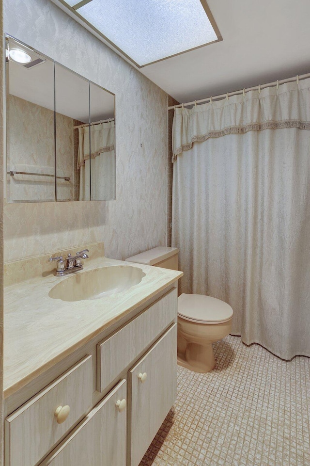 bathroom with tile patterned floors, toilet, a shower with curtain, vanity, and a skylight