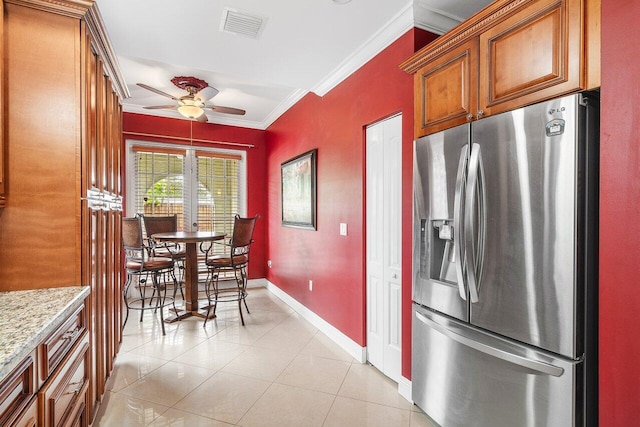 kitchen featuring ceiling fan, light tile patterned flooring, crown molding, light stone countertops, and stainless steel fridge