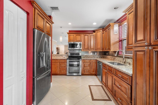 kitchen featuring light stone counters, ornamental molding, appliances with stainless steel finishes, pendant lighting, and sink