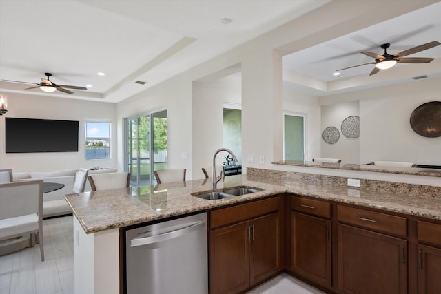 kitchen with sink, stainless steel dishwasher, kitchen peninsula, a raised ceiling, and light stone countertops