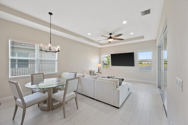 interior space with light hardwood / wood-style flooring, a tray ceiling, and ceiling fan with notable chandelier