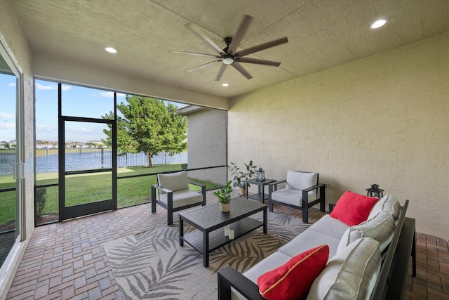 sunroom / solarium featuring a water view and ceiling fan