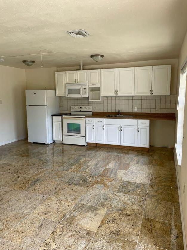 kitchen featuring white cabinetry, white appliances, sink, and backsplash