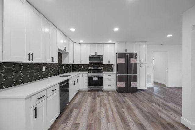 kitchen featuring white cabinets, sink, light hardwood / wood-style flooring, decorative backsplash, and stainless steel appliances