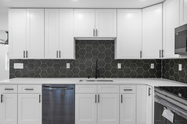 kitchen with decorative backsplash, white cabinetry, sink, and appliances with stainless steel finishes