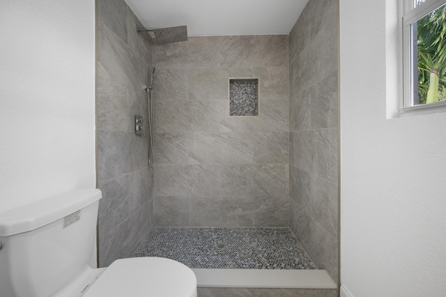 bathroom featuring toilet and tiled shower