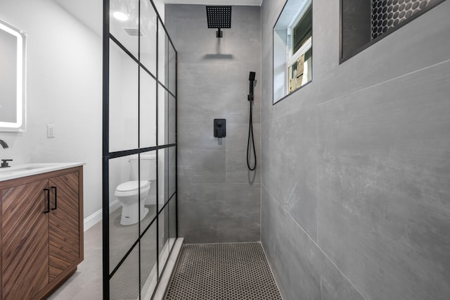 bathroom with a tile shower, vanity, and toilet