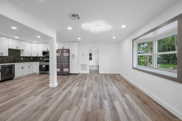 kitchen featuring backsplash, white cabinetry, stainless steel appliances, and light wood-type flooring