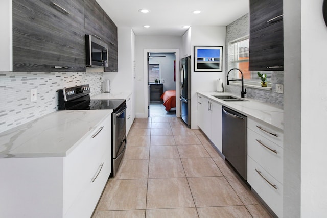 kitchen featuring white cabinetry, stainless steel appliances, sink, and light stone countertops