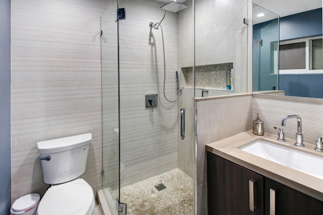 bathroom with toilet, vanity, an enclosed shower, and tile walls