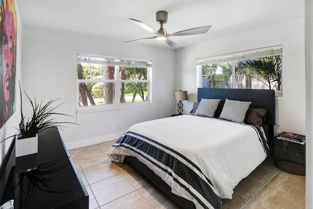 tiled bedroom with ceiling fan and multiple windows