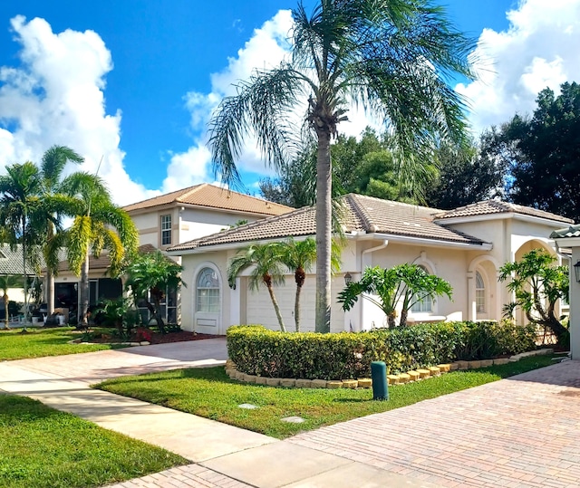 mediterranean / spanish-style home with a garage and a front lawn