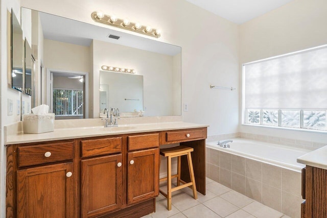 bathroom featuring tile patterned floors, a relaxing tiled tub, and vanity