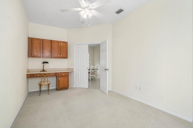 interior space with light carpet, ceiling fan, and built in desk