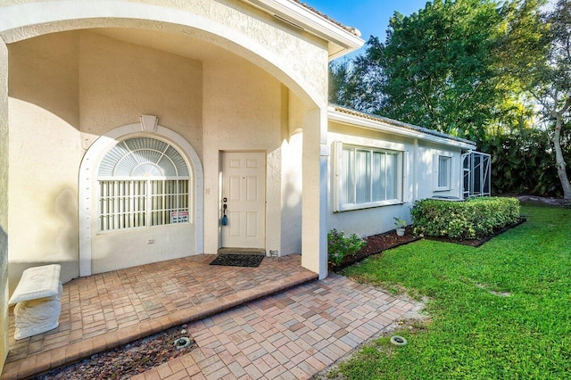 entrance to property featuring a lawn and a patio