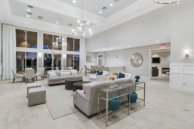 living room featuring a tray ceiling, a fireplace, a towering ceiling, and light hardwood / wood-style floors