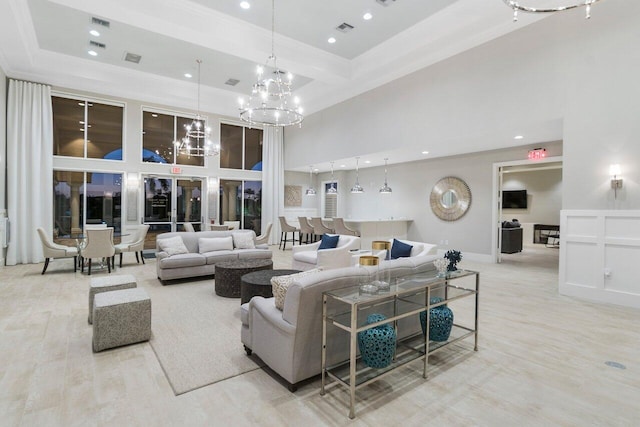 living room with light wood-type flooring, a towering ceiling, and an inviting chandelier