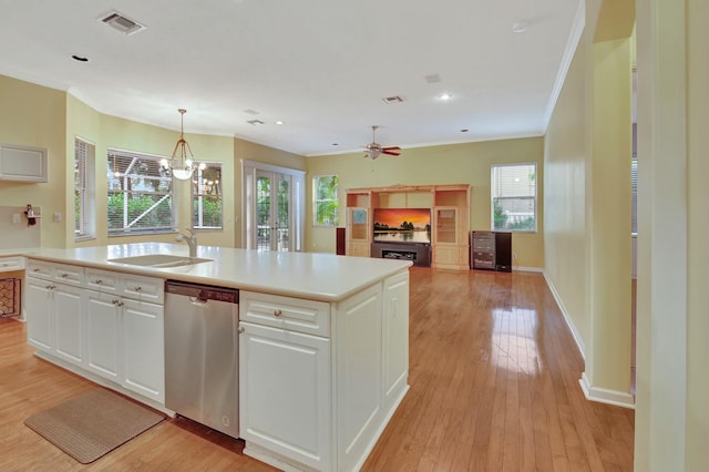 kitchen featuring stainless steel dishwasher, plenty of natural light, white cabinetry, and decorative light fixtures