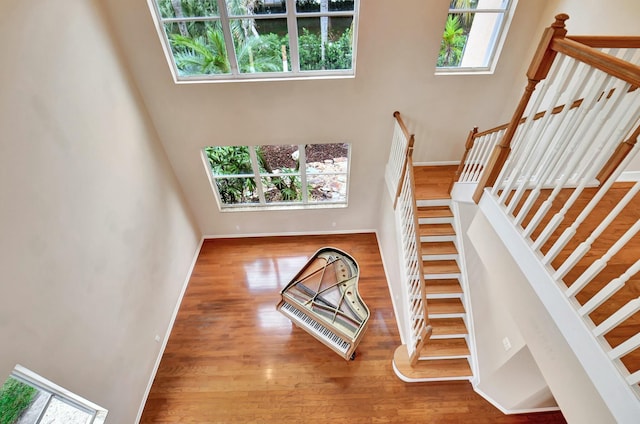 stairway with wood-type flooring and a high ceiling