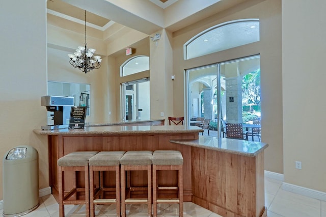 bar with light tile patterned flooring, decorative light fixtures, ornamental molding, and a notable chandelier