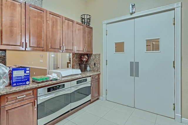 kitchen with decorative backsplash, stainless steel oven, light stone counters, and light tile patterned floors