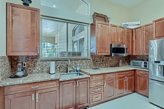 kitchen featuring appliances with stainless steel finishes, backsplash, light stone counters, and sink