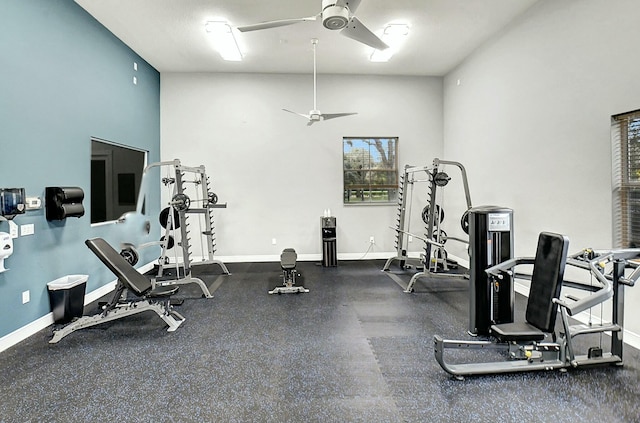 exercise room with ceiling fan and a towering ceiling