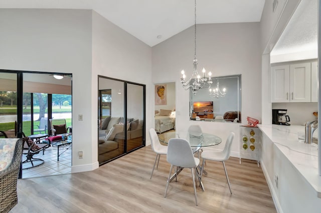 dining space with high vaulted ceiling, light hardwood / wood-style floors, and a chandelier