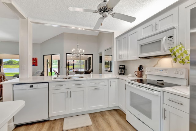 kitchen with a textured ceiling, kitchen peninsula, sink, and white appliances